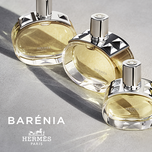 Imagem da vitrine com três frascos do perfume Barénia da Hermès sobre superfície iluminada. Só na Kassio Perfumaria